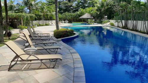 a row of lounge chairs next to a swimming pool at Mediterrâneo Flat in Rio de Janeiro