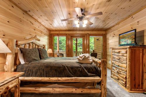 uma cabina de madeira no quarto com uma cama e uma ventoinha de tecto em Mountain Cinema Lodge em Pigeon Forge