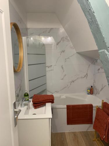 une salle de bain avec un lavabo et une baignoire dans l'établissement Charmant appartement rénové, à Bayeux