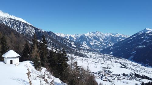 a snow covered mountain range with a small white building at Budamerhof in Virgen