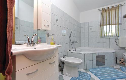 a bathroom with a sink and a toilet and a tub at 3 Bedroom Gorgeous Apartment In Marcana in Marčana