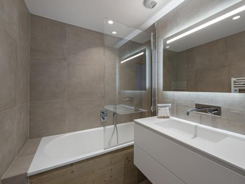 une salle de bain avec une baignoire, un lavabo et un miroir dans l'établissement Appartement moderne avec cheminée et terrasse - Près des pistes et commerces - FR-1-565-63, à Les Allues