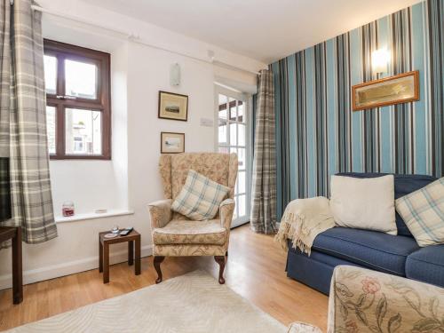 a living room with a blue couch and a chair at Daffodil Cottage in Grange Over Sands