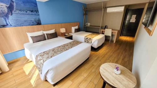 a hotel room with two beds and a table at Hotel El Tambo 2 in Lima