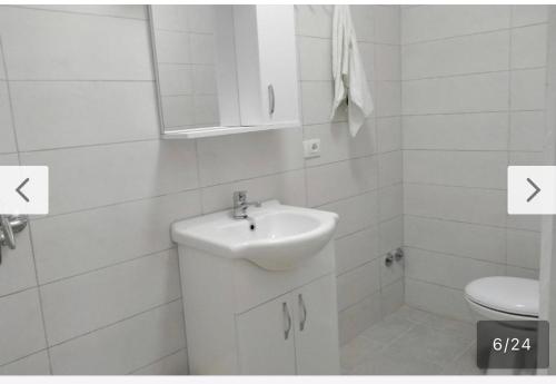 a white bathroom with a sink and a toilet at Home guest in Tirana