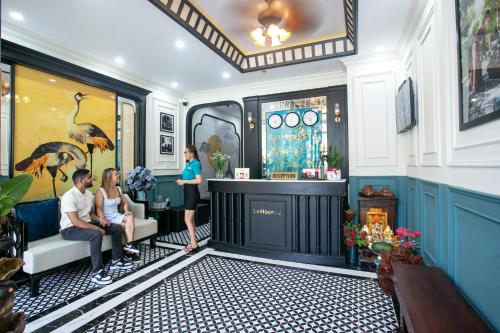a group of people sitting around a bar in a room at Le House Hotel and Studio in Danang