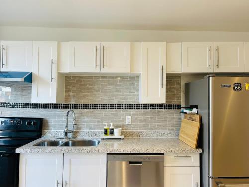 a kitchen with white cabinets and a stainless steel refrigerator at SAI GON Suit in Grimsby