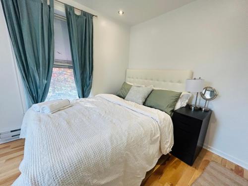 a white bedroom with a bed and a window at SAI GON Suit in Grimsby