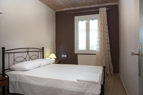a bedroom with a white bed and a window at Nafsika House in Ayios Kirikos