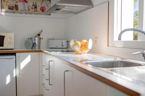 a white kitchen with a sink and a window at Apartamentos Turisticos CAN CUNILL in Es Pujols