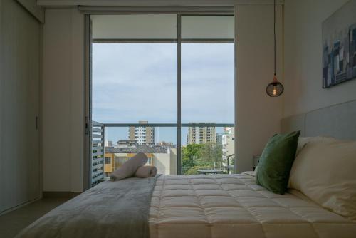 a large bed in a room with a large window at Distrito 90 - Estudios y Apartamentos para vacaciones y viajes de negocio in Barranquilla
