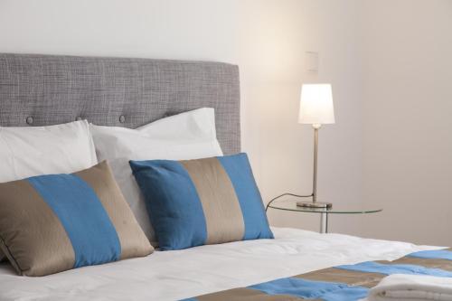 リスボンにあるDowntown Cozy Apartmentのベッド(青と白の枕、ランプ付)