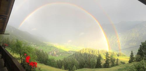 a rainbow over a green valley with a rainbow at Budamerhof in Virgen