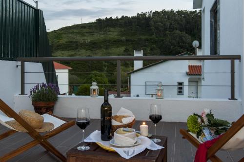 a table with a bottle of wine and glasses on a balcony at Beachouse - Surf, Bed & Breakfast in Ericeira