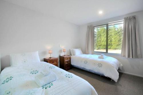 ワナカにあるMatukituki Lodgeのベッドルーム1室(ベッド2台、窓付)