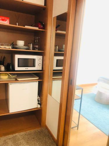 a kitchen with a microwave and a door into a room at Suite like Sweet By StaySalmar in Torres Vedras