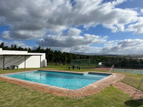 ein Schwimmbad in der Mitte eines Gartens in der Unterkunft The Lake House - Theewaterskloof Golf Estate in Villiersdorp