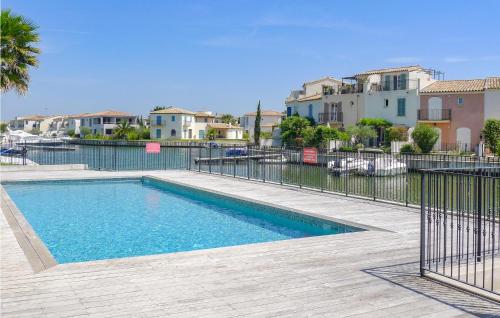a swimming pool with a fence and some buildings at Cozy Home In Aigues-Mortes With Wifi in Aigues-Mortes