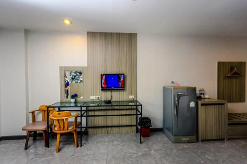 a room with a table and a refrigerator and chairs at Embryo Hotel  in Pattaya Central