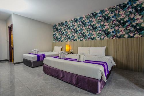 two beds in a room with a painting on the wall at Embryo Hotel  in Pattaya Central