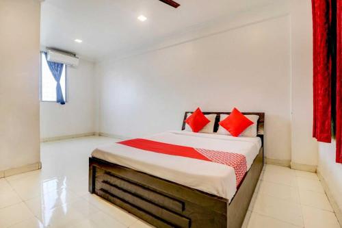 a bedroom with a large bed with red pillows at Hotel O Sai Residency in Pune