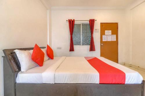 a bedroom with a bed with red pillows and a window at Hotel O Sai Residency in Pune