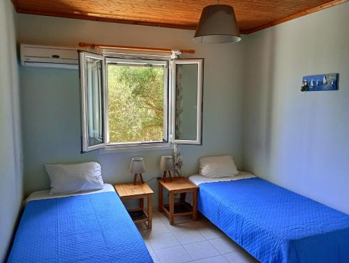 two beds in a room with a window at Xigia hideaway - panoramic sea view house in Zakynthos Town