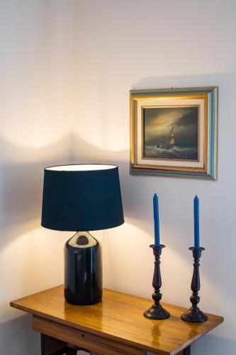 a table with a lamp and two blue candles on it at Rio Beach Residence in Patra