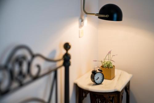 a lamp and a table with a clock and a potted plant at Rio Beach Residence in Patra
