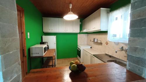 a kitchen with green walls and a table with fruit on it at Xigia hideaway - panoramic sea view house in Zakynthos Town