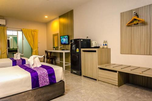 a hotel room with two beds and a refrigerator at Embryo Hotel  in Pattaya Central