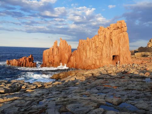 a large rock formation in the ocean next to the ocean at Villetta Il Faro sul Mare in Àrbatax