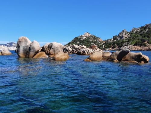 a body of water with rocks in the water at Villetta Il Faro sul Mare in Àrbatax