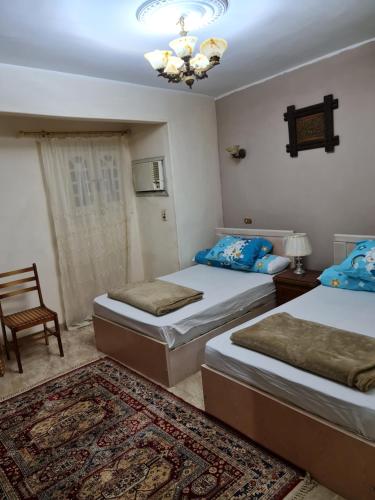 a bedroom with two beds and a chandelier at Hello Pyramids inn in Cairo