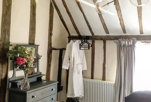 um quarto com uma cómoda e um vaso de flores em Blacksmith's Cottage Suffolk em Lavenham