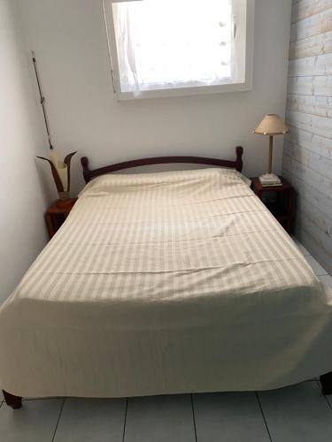 ein großes Bett in einem Schlafzimmer mit Fenster in der Unterkunft Bungalow Belfond Plage Pointe Marin in Sainte-Anne