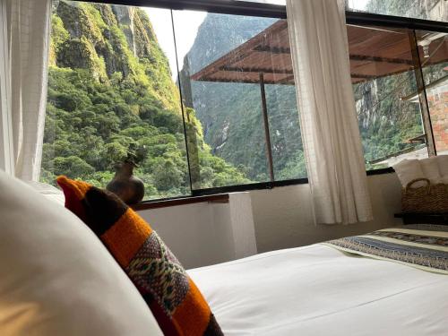 a bedroom with a large window with a mountain view at SACRED STONE Boutique Hotel in Machu Picchu