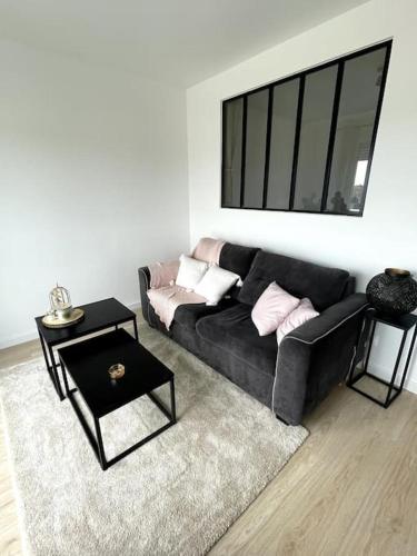 a living room with a black couch and a table at appartement cosy et lumineux in Orly