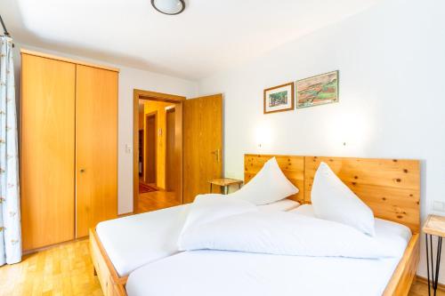 a bedroom with a white bed and a wooden headboard at Appart Taverne in Mayrhofen