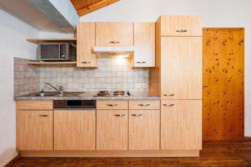 a kitchen with wooden cabinets and a sink at Appart Taverne in Mayrhofen