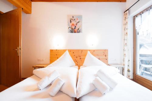 a bedroom with a white bed with white pillows at Appart Taverne in Mayrhofen