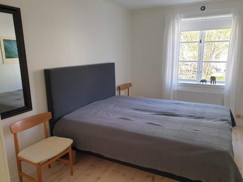 1 dormitorio con 1 cama, 1 silla y 1 ventana en Välrenoverad fin lägenhet i charmigt område en Söderhamn