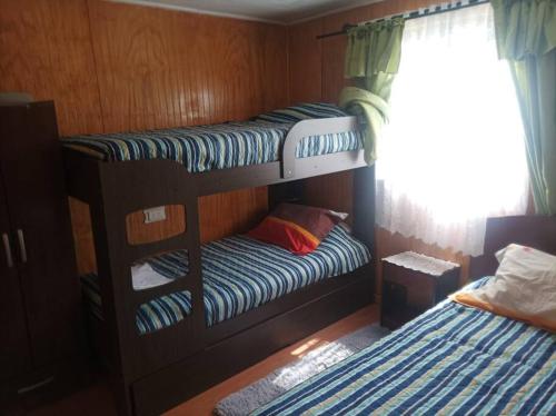 a bedroom with two bunk beds and a window at Cabaña ANN in Curiñanco