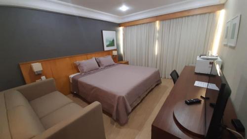 a hotel room with a bed and a couch and a desk at Mediterrâneo Flat in Rio de Janeiro
