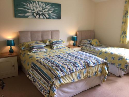 a bedroom with two beds and two lamps on tables at Bryn Derw in Talsarnau