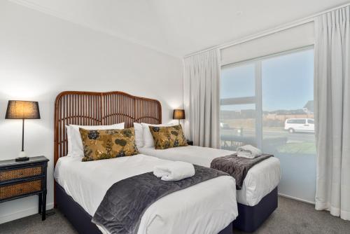 two beds in a hotel room with a window at Nga Roto Retreat - Taupo in Taupo