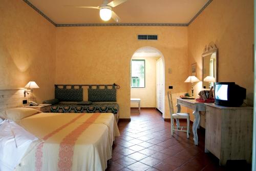 a bedroom with a bed and a desk and a television at iGV Club Baia Samuele in Sampieri