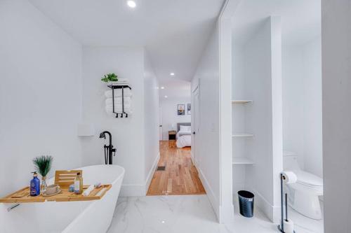 uma casa de banho branca com uma banheira e um lavatório em Modern Red Door Haven +5mins to Boston em Milton