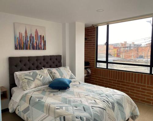 a bedroom with a bed with a blue pillow on it at Moderno apartamento cerca al aeropuerto in Bogotá