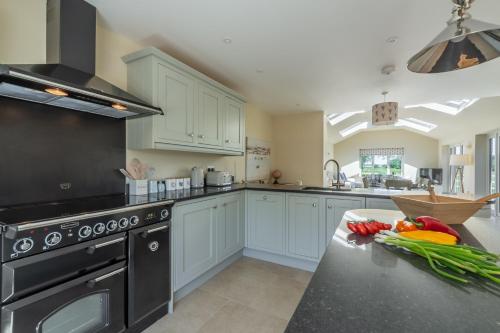 a kitchen with white cabinets and a black stove top oven at Flint House W in Wighton